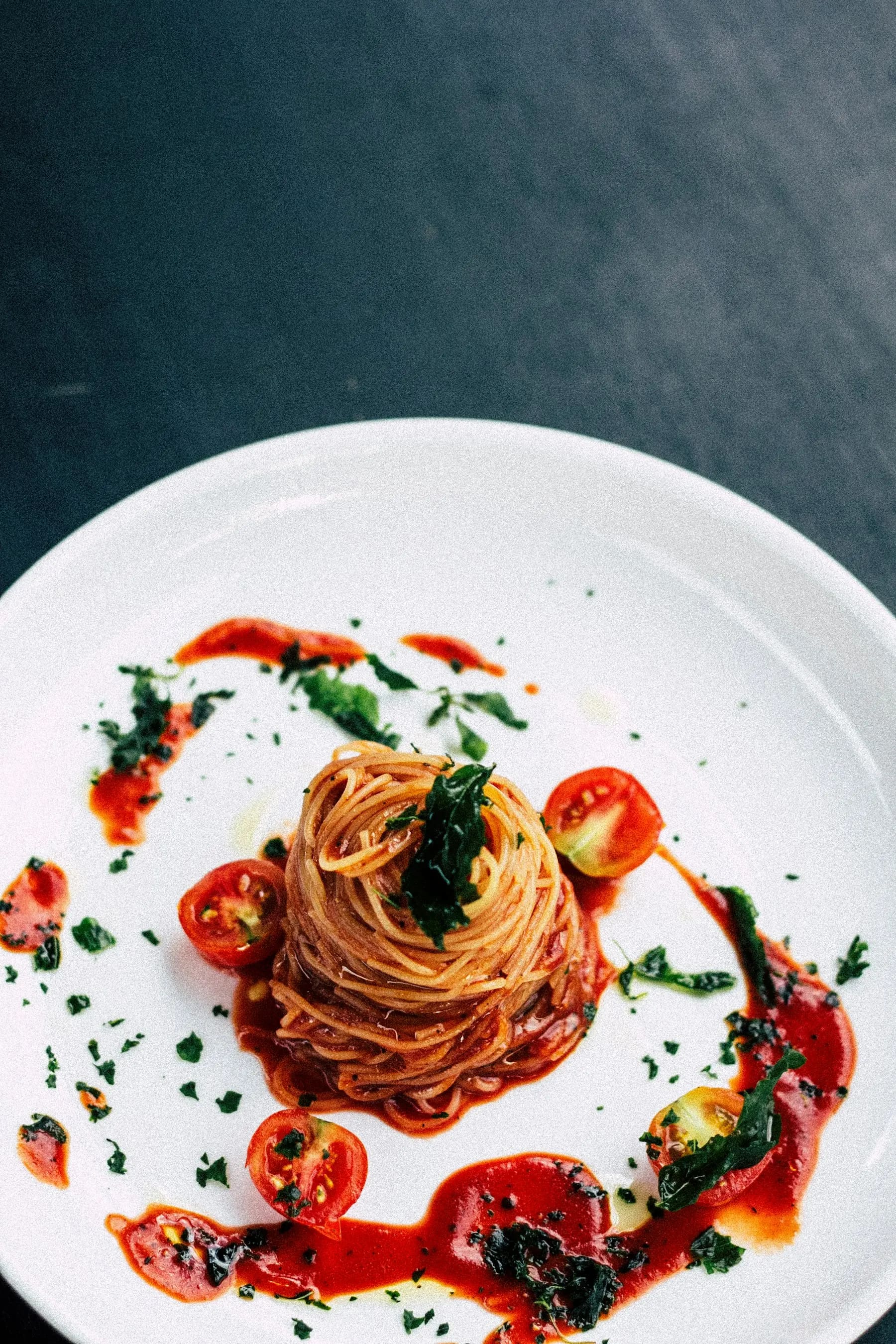Une assiette de spaghetti à la tomate et au basilic, sur une table sombre